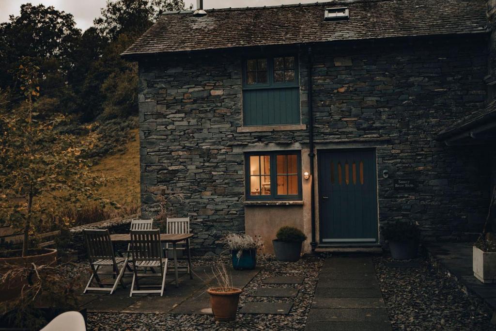 una casa di pietra con una porta blu e sedie di SUNNY BROW BARN at Sunny Brow Farm ad Ambleside