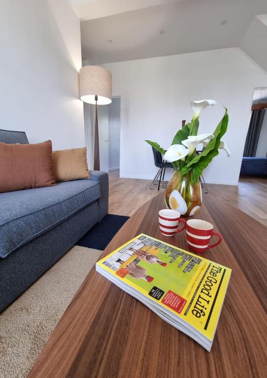 - un salon avec un canapé et un magazine dans l'établissement LAGUNE ÉLÉGANTE CENTRE spacieux et à 5 min de la plage, à Dinard