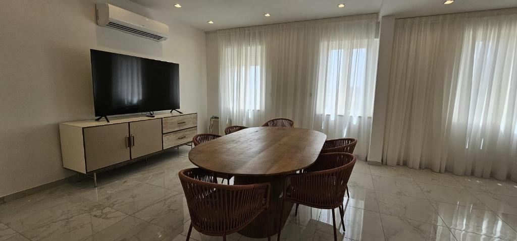 a dining room with a table and a flat screen tv at Modern Elegance Valletta Apartment V1 in Valletta