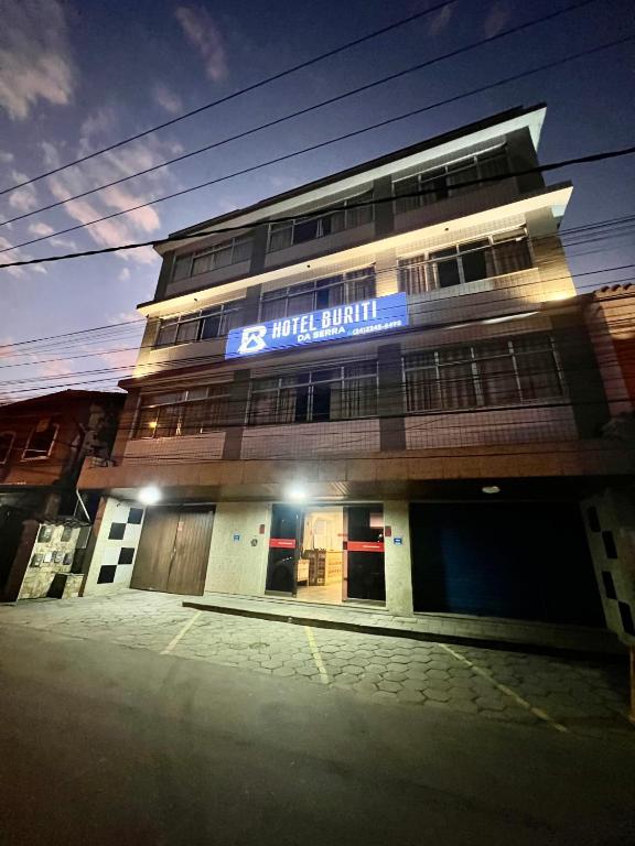 a building with a blue sign on the side of it at Hotel Buriti da Serra in Itaipava