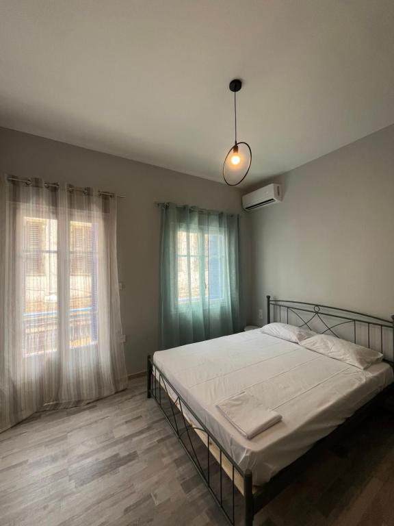 a bedroom with a bed and two windows at Χαβίνη 35 in Amfilochía