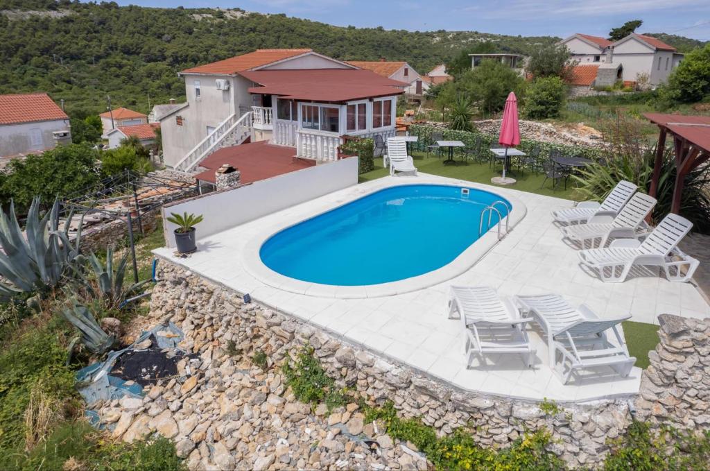 a swimming pool with chairs and a house at Apartments Ruža Dragove Dugi otok in Dragove