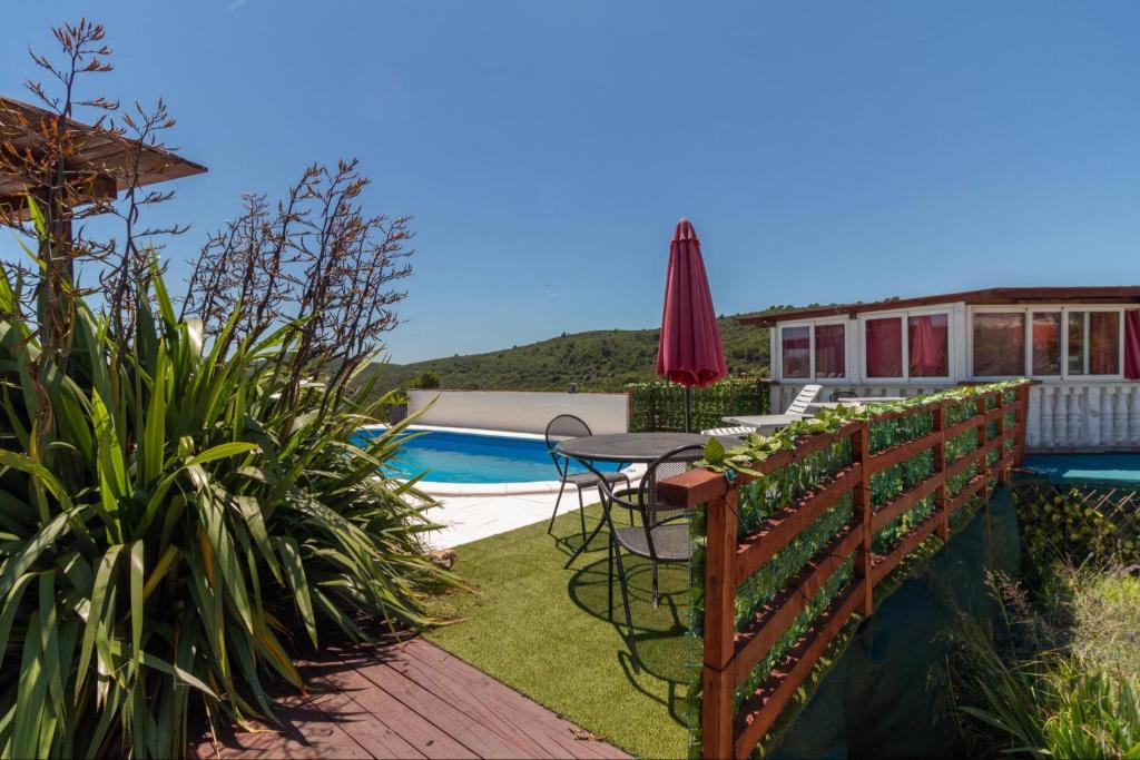 a patio with a table and umbrella next to a pool at Apartments Ruža Dragove Dugi otok in Dragove