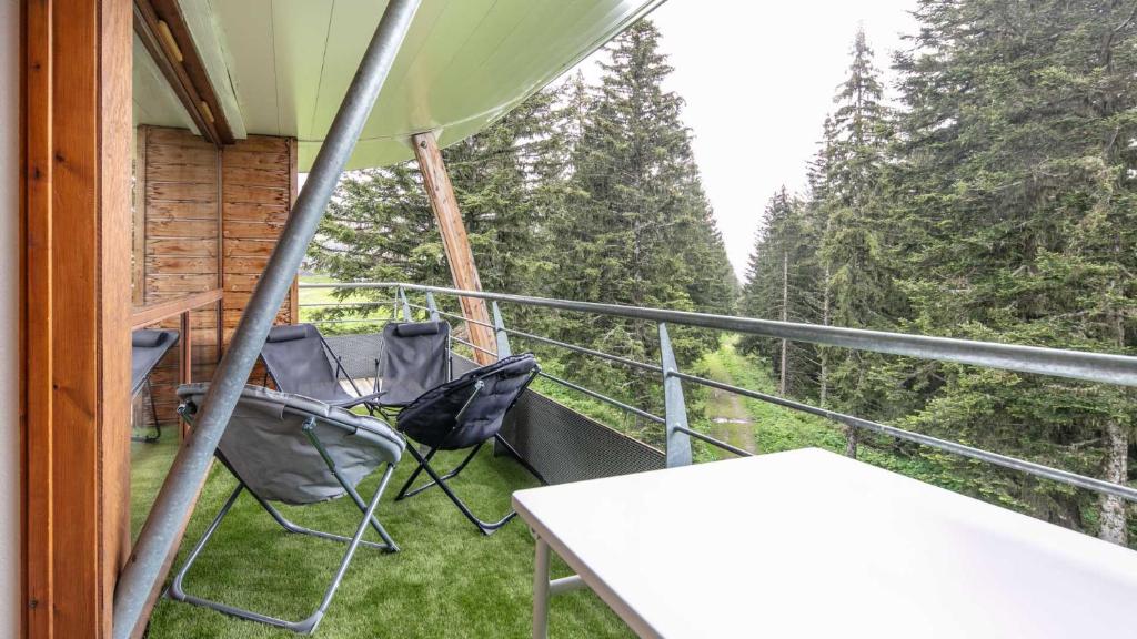 - une terrasse couverte avec 2 chaises et une table sur un balcon dans l'établissement V DU BACHAT - Asters D22 - Appt 5 pers, à Chamrousse