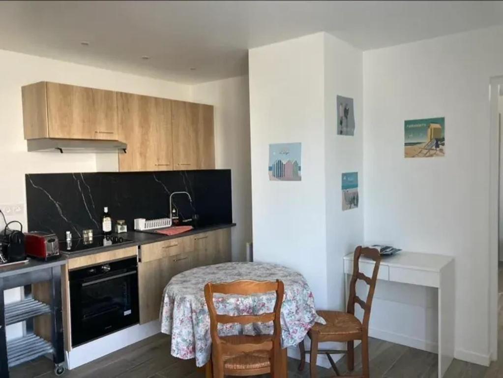 une cuisine avec une table et des chaises dans une pièce dans l'établissement Appartement charmant aux Sables-d'Olonne avec terrasse., à Les Sables-dʼOlonne