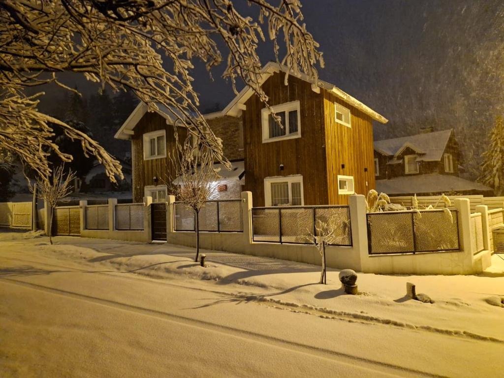 a wooden house with a fence in the snow at Cabañas Los Manzanos in San Martín de los Andes