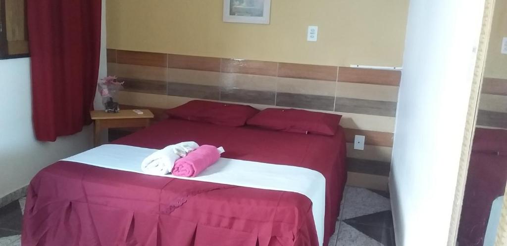 a bed with a pink and white pillow on it at pousada chykos in Barreirinhas