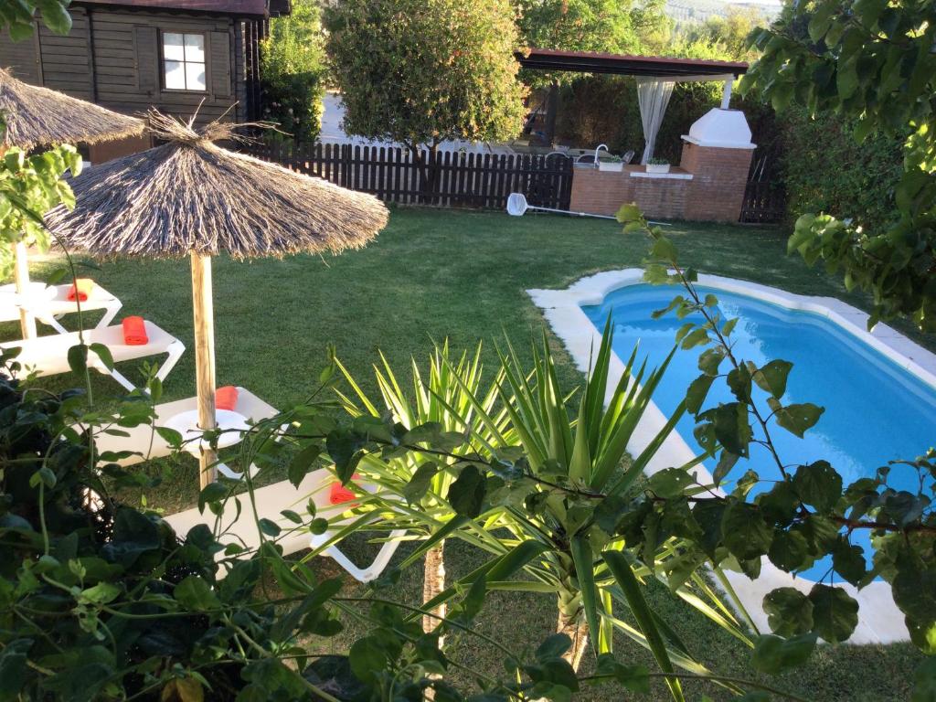 un patio trasero con una piscina con sombrilla y sillas en Casa Rural Las Bodegas, en Setenil