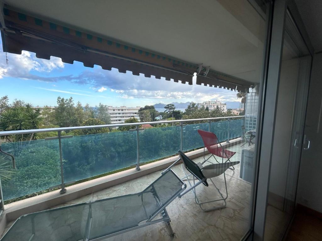 un balcon avec deux chaises et une vue sur une ville dans l'établissement A078 Bel appartement spacieux avec Piscine et vue mer, à Cannes