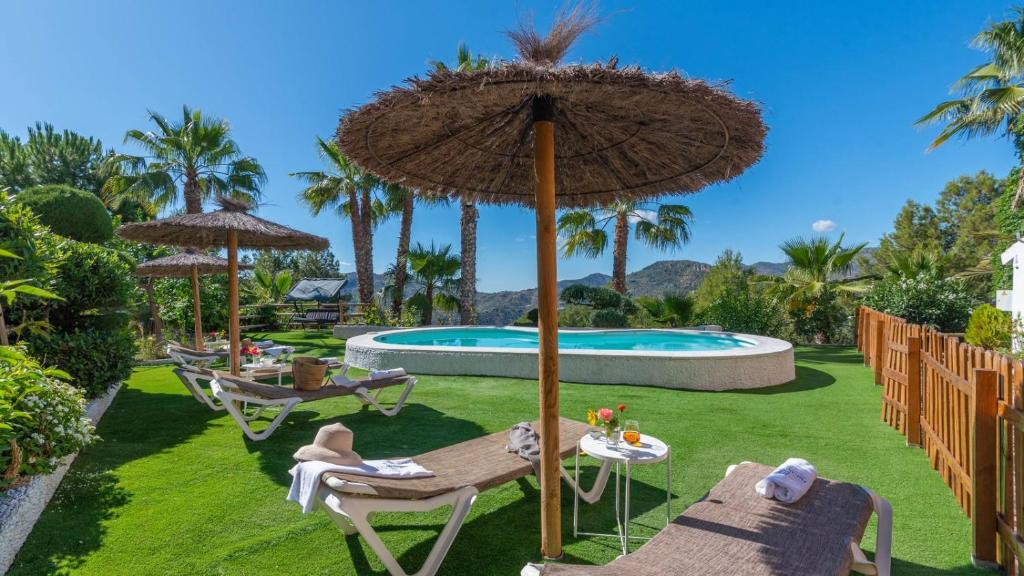 patio z parasolem i krzesłami oraz basenem w obiekcie Villa Gran Solano Colmenar by Ruralidays w mieście Colmenar