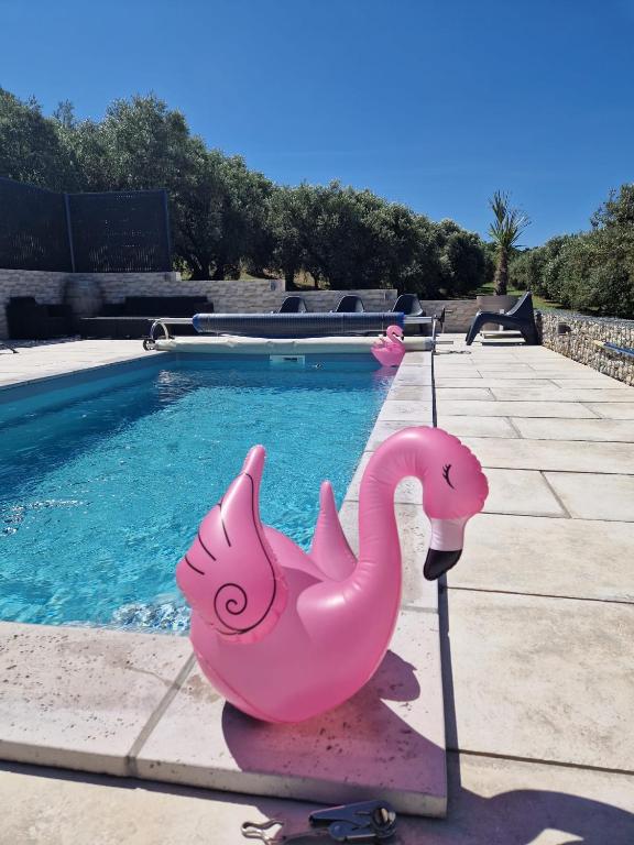 une statue rose de flamant près d'une piscine dans l'établissement Villa climatisée avec Piscine privée, à Volonne