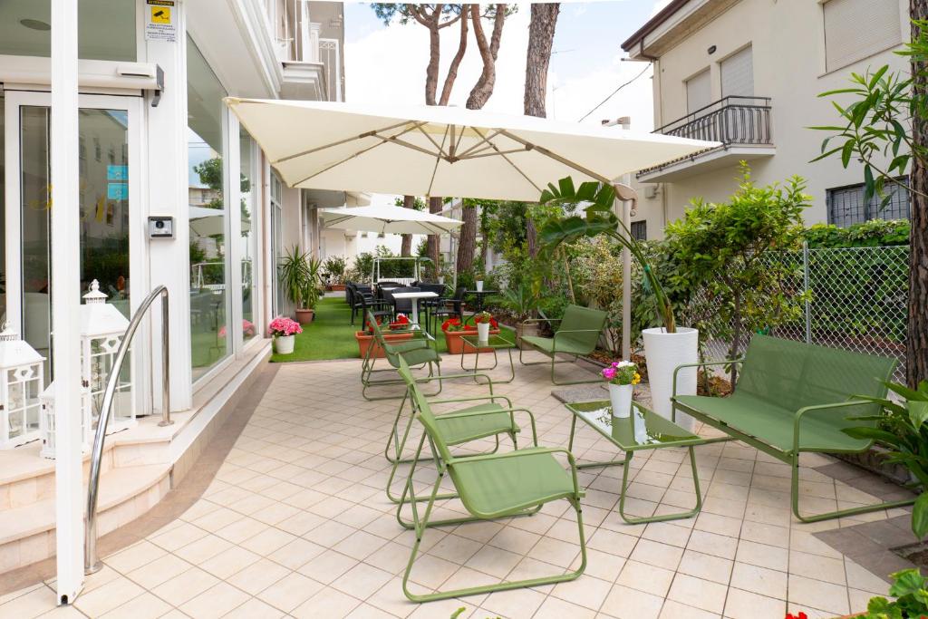 patio z zielonymi krzesłami i parasolem w obiekcie Hotel Negresco w mieście Riccione