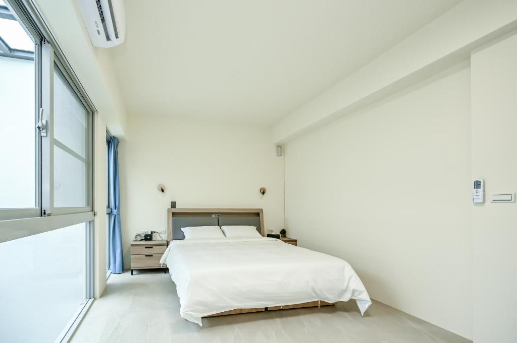 una camera da letto bianca con un letto e una finestra di Douhao B&B a Zhongpu