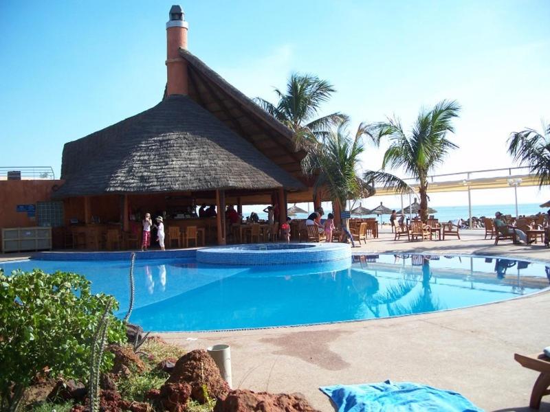 a large swimming pool with a pavilion next to the beach at Résidence Safari Village in Saly Portudal