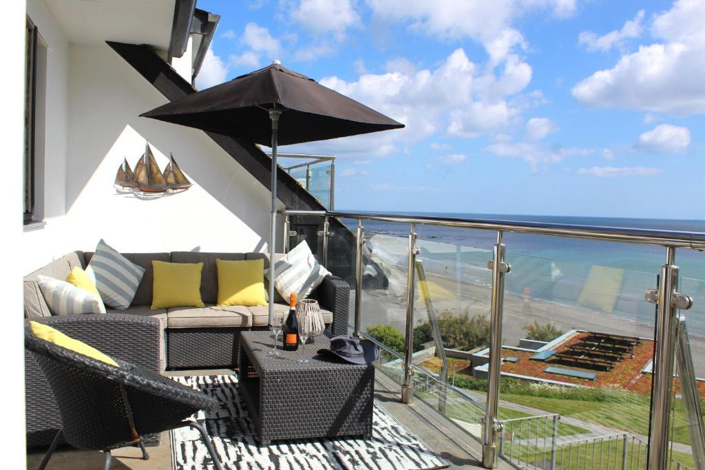 a balcony with a couch and an umbrella at Apartment 19 in Downderry