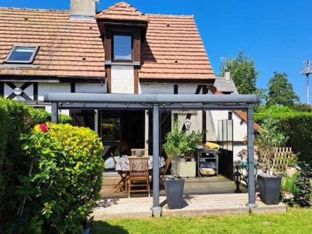 Cette maison dispose d'une terrasse couverte avec une table et des chaises. dans l'établissement Le Clos du Golf, à Cabourg