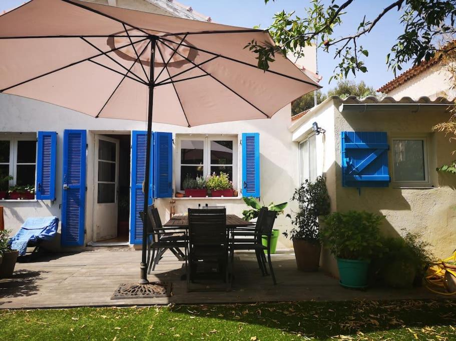 un patio avec une table, des chaises et un parasol dans l'établissement Studio avec kitchenette salle de bain et wc partagé, à Toulon