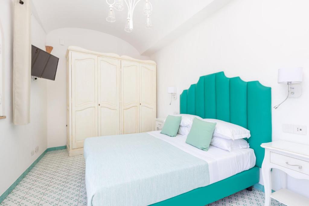 a bedroom with a white bed with a green headboard at Villa Nannina in Positano