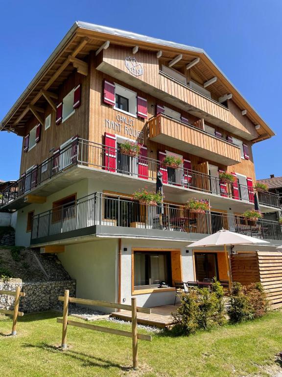 - un grand bâtiment avec des balcons, des tables et un parasol dans l'établissement Chalet Nant Rouge, aux Contamines-Montjoie