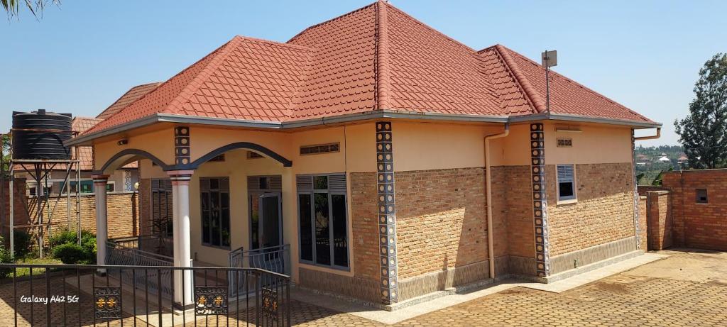 a small brick house with a red roof at GUESTHOUSE MAC Terranova in Rwamagana