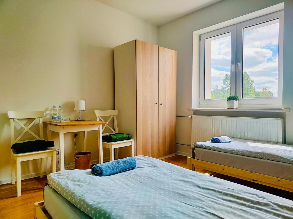 a bedroom with two beds and a desk and a window at Dom Bez Ścian in Gubin