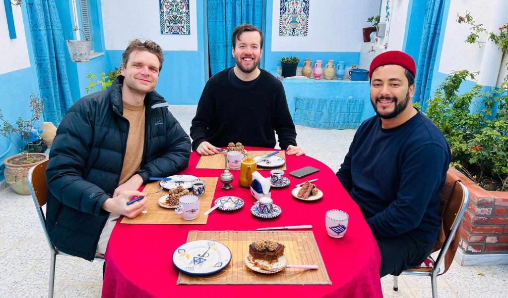 a group of three men sitting at a table with food at Dar Hkaïem in Sousse