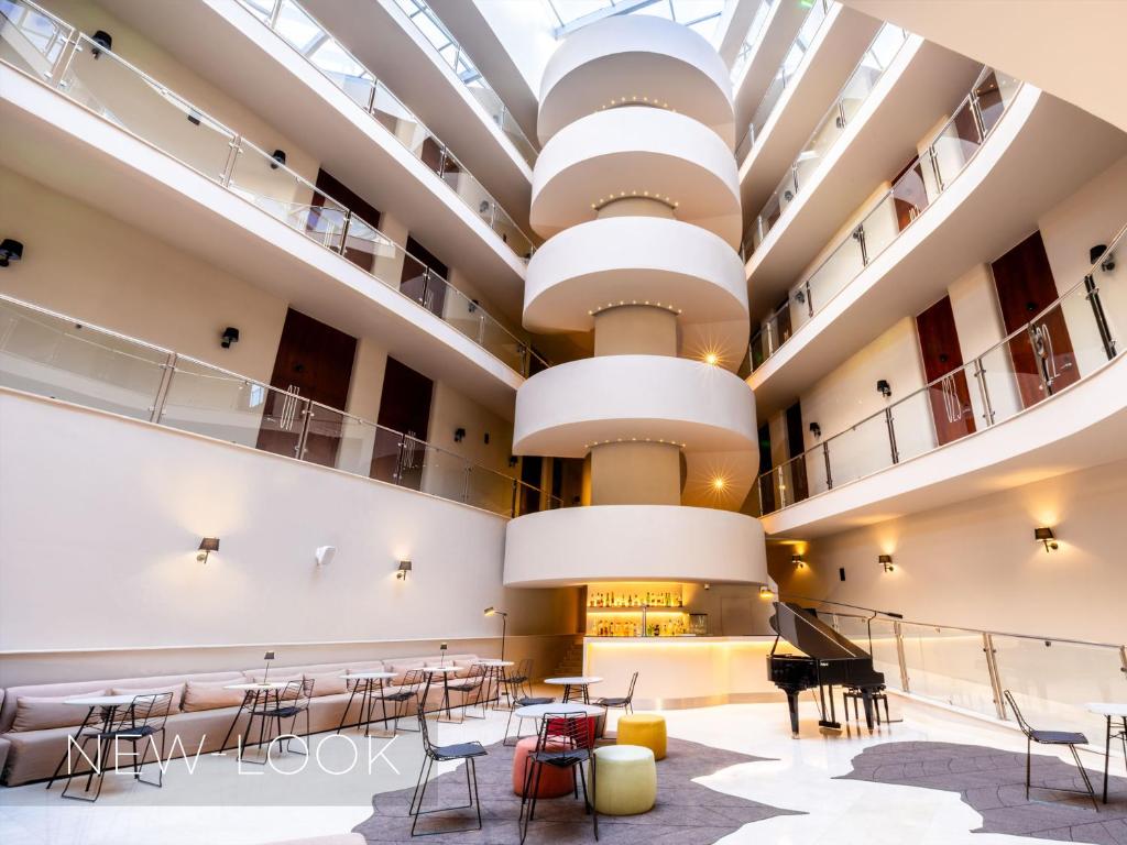 a large hall with tables and chairs and a grand piano at Aqua Pedra Dos Bicos Design Beach Hotel - Adults Friendly in Albufeira