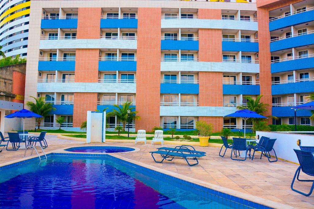 a hotel with a pool and chairs and a building at TerrazzoPontaNegraDJ in Natal