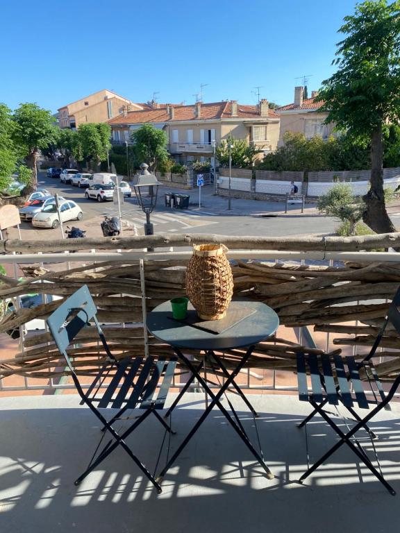 d'une table, de chaises et d'un vase sur le balcon. dans l'établissement MAISON CABROL, à Carqueiranne