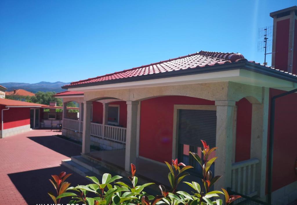 ein rotes Gebäude mit einer Veranda auf einer Straße in der Unterkunft Casa Valente in Ponte da Barca