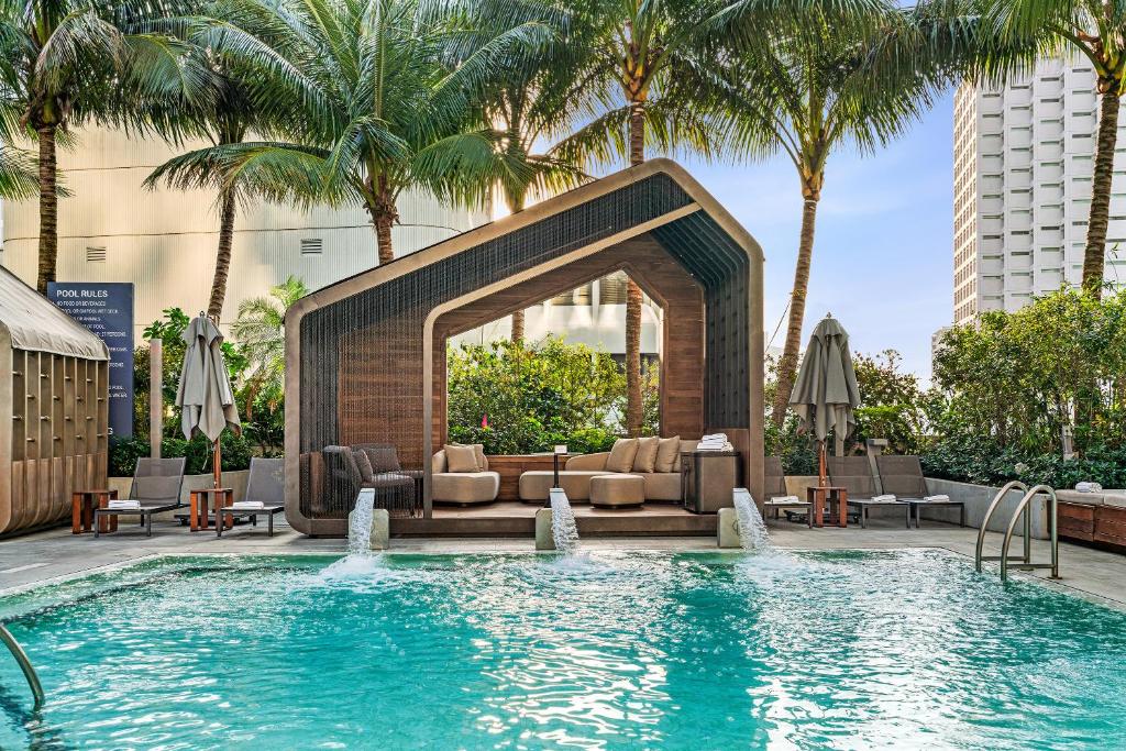 a pool with a couch and chairs and palm trees at EAST Miami in Miami