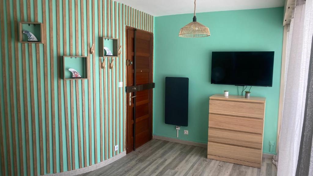 a living room with a television and a wooden dresser at Appartement bord de mer Palavas in Palavas-les-Flots