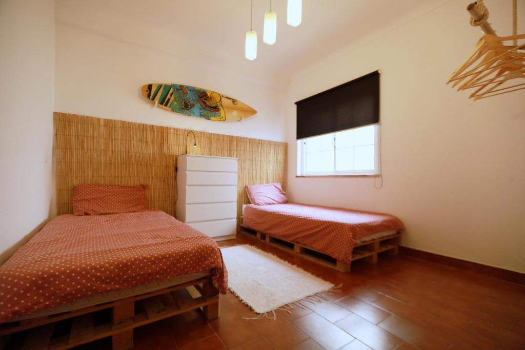 a bedroom with two beds and a surfboard on the wall at Surf House in Aljezur