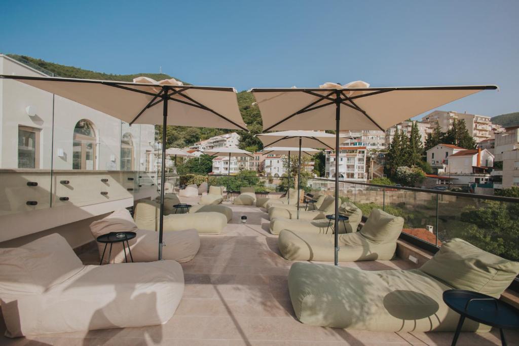 a row of white couches and umbrellas on a balcony at Infinity Hotel & More in Budva