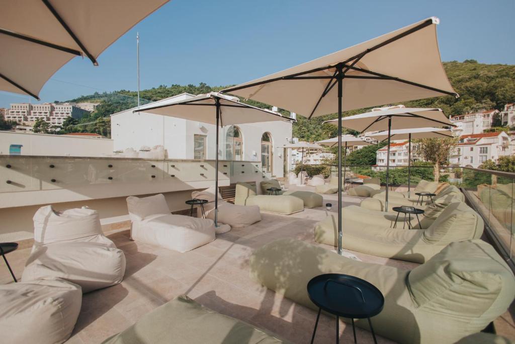 a patio with white couches and umbrellas at Infinity Hotel & More in Budva