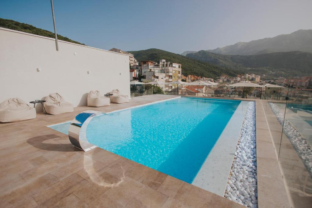 a swimming pool on the roof of a house with mountains at Infinity Hotel & More in Budva
