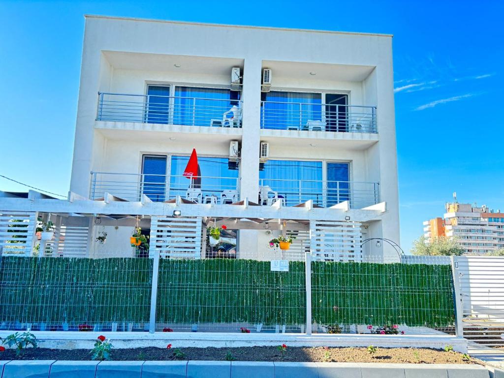 a white apartment building with a fence in front of it at Waterman in Costinesti