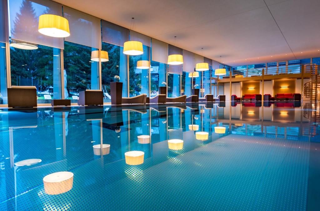 a swimming pool with chairs and lights in a building at The Christiania Mountain Spa Resort in Zermatt