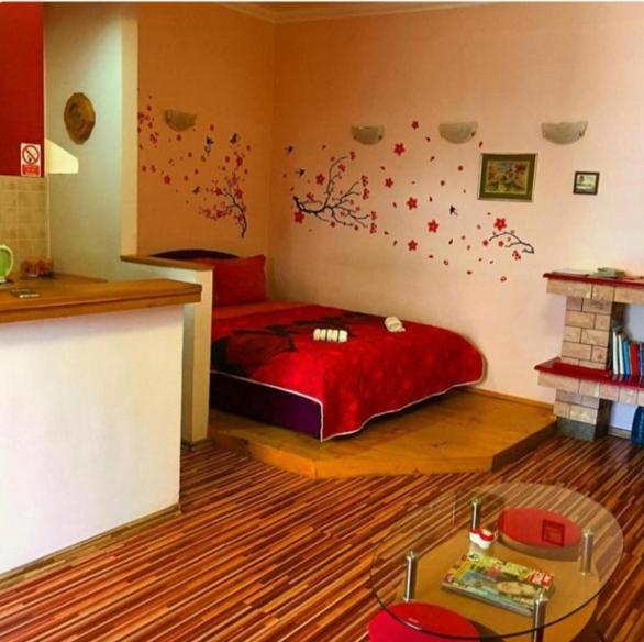 Un dormitorio con una cama con sábanas rojas y flores en la pared. en The heart of Bascarsija, en Sarajevo
