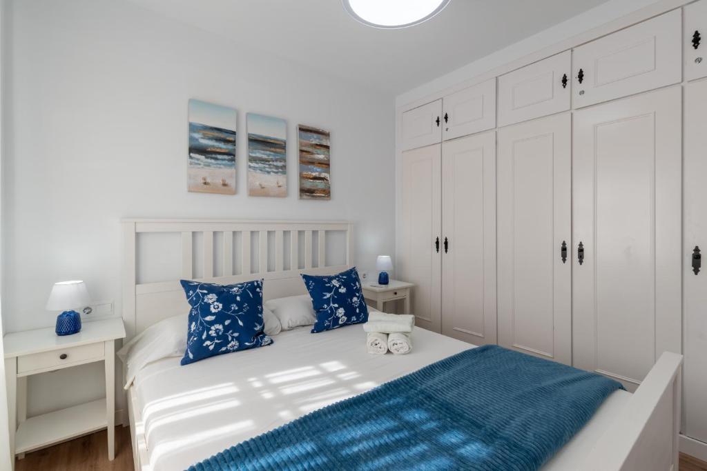 a bedroom with white cabinets and a bed with blue pillows at Renovated apartment on beachside with pool in Nerja