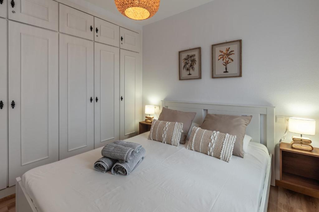 a bedroom with a white bed with two pillows at Renovated apartment on beachside with pool in Nerja