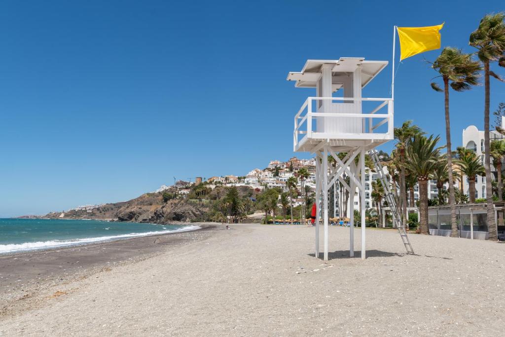 a life guard stand on a beach with a yellow flag at Renovated apartment on beachside with pool in Nerja