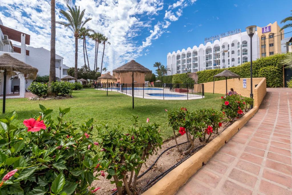 a resort with a garden and a swimming pool at Renovated apartment on beachside with pool in Nerja