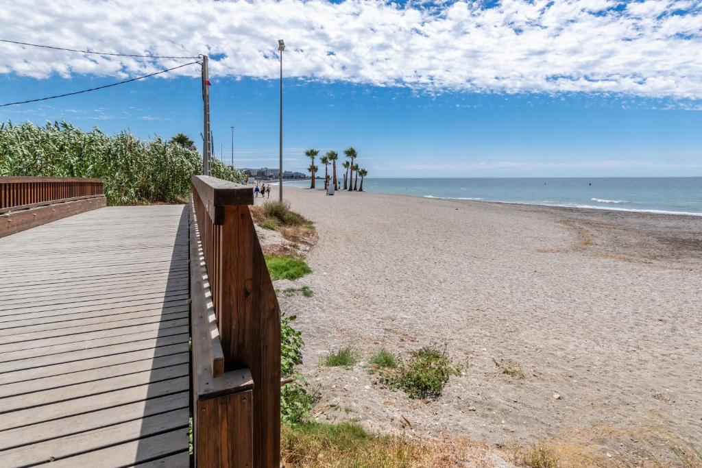a boardwalk on a beach with palm trees and the ocean at Renovated apartment on beachside with pool in Nerja