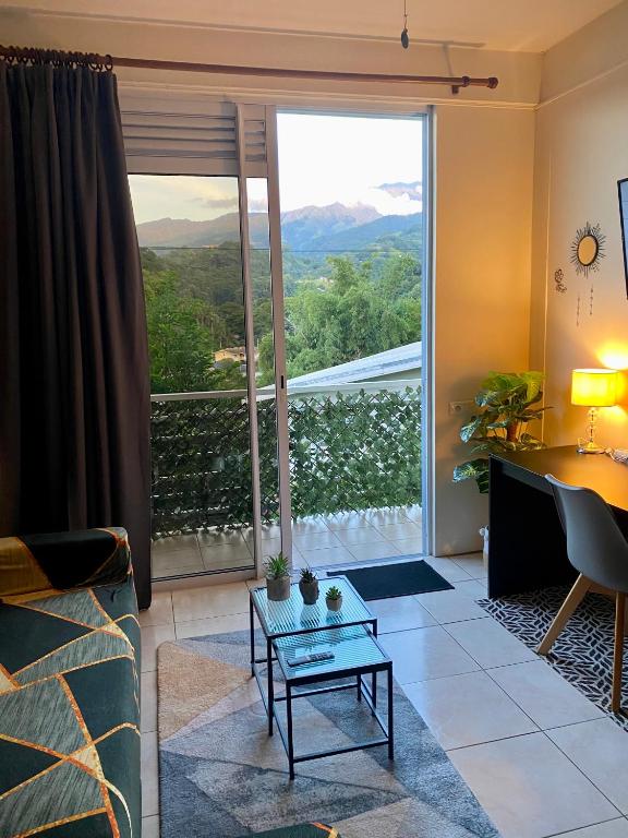 a living room with a couch and a large window at Heiata Lodge Papeete in Papeete