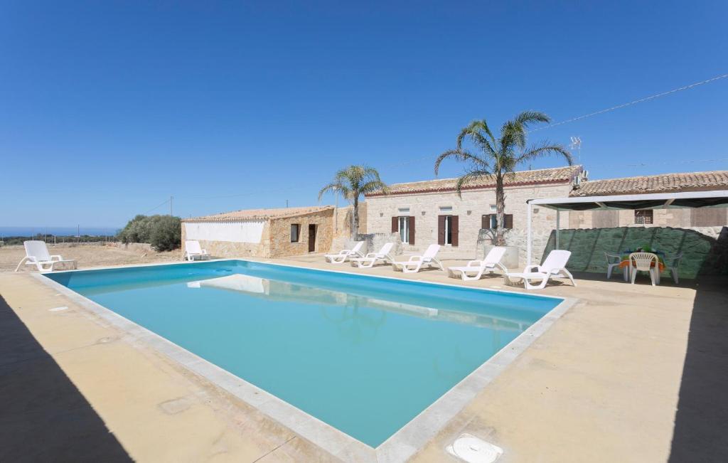 ein großer Swimmingpool mit Stühlen und einem Haus in der Unterkunft Cozy Home In Santa Croce Camerina in Santa Croce Camerina