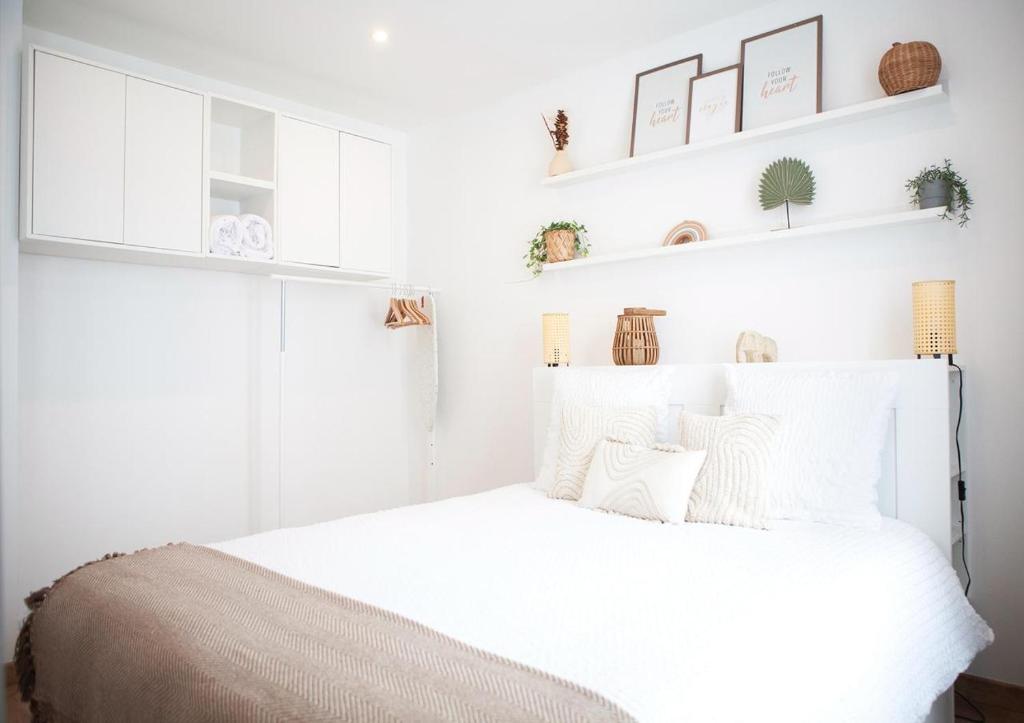 a bedroom with a white bed with white walls and shelves at 2 Pièces Cosy - Mairie Des Lilas in Les Lilas