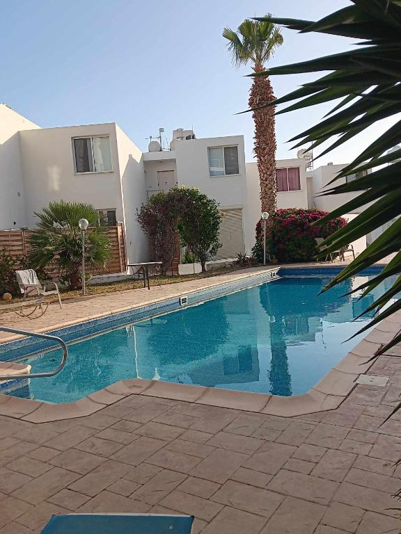a swimming pool in front of a house with a palm tree at Summer Bliss Apartment Peyia in Peyia
