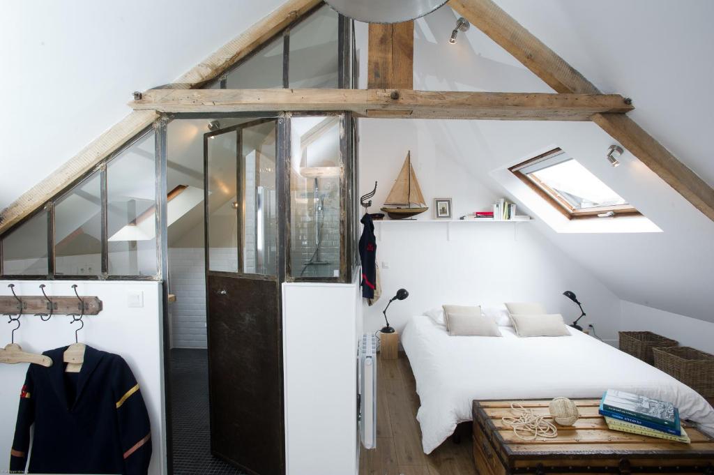 een slaapkamer met een wit bed en glazen wanden bij Appartements du Port in Port-en-Bessin-Huppain
