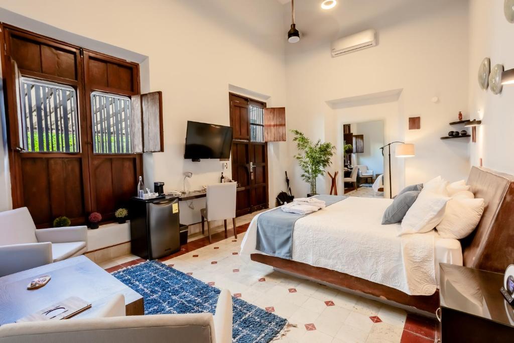 ein Schlafzimmer mit einem Bett und einem Schreibtisch in einem Zimmer in der Unterkunft Kuxtal Hotel Boutique in Mérida